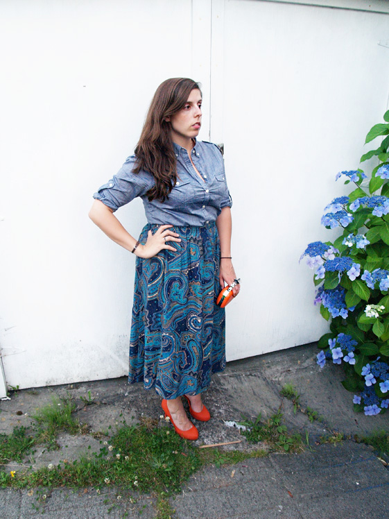 blue paisley mid length skirt, chambray shirt, and orange pumps and clutch
