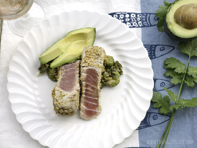 sesame and wasabi crusted tuna on a plate with avocado and brussel sprouts