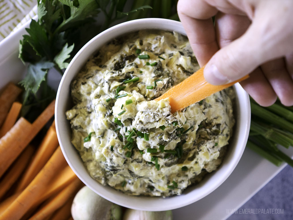 person dipping carrot into a healthy celery root dip 