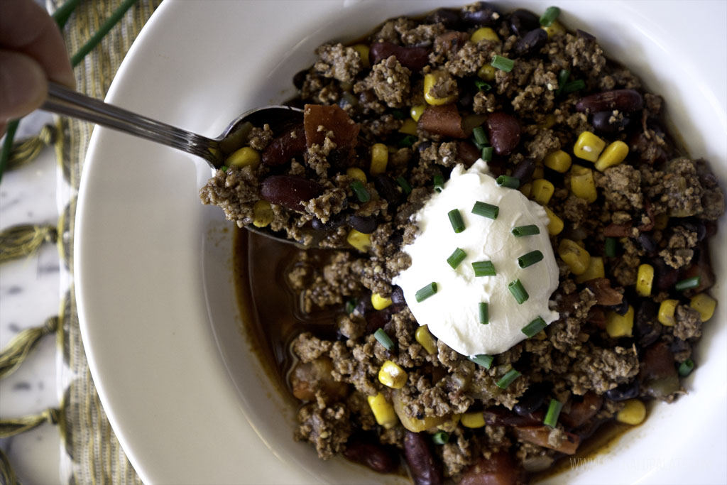 Bowl of turkey chili with cocoa powder topped with sour cream