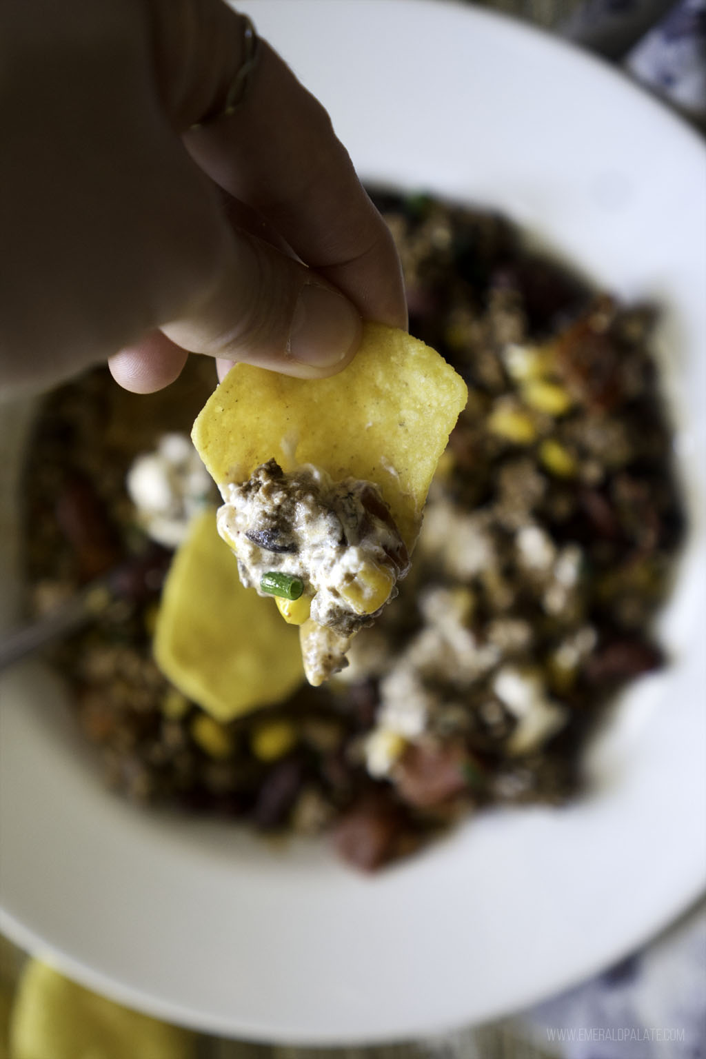 person holding up tortilla chip with turkey chili