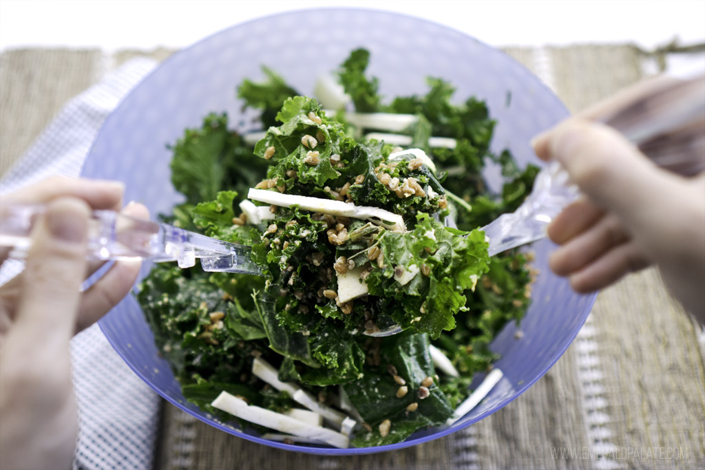 Person tossing power kale salad recipe with tongs
