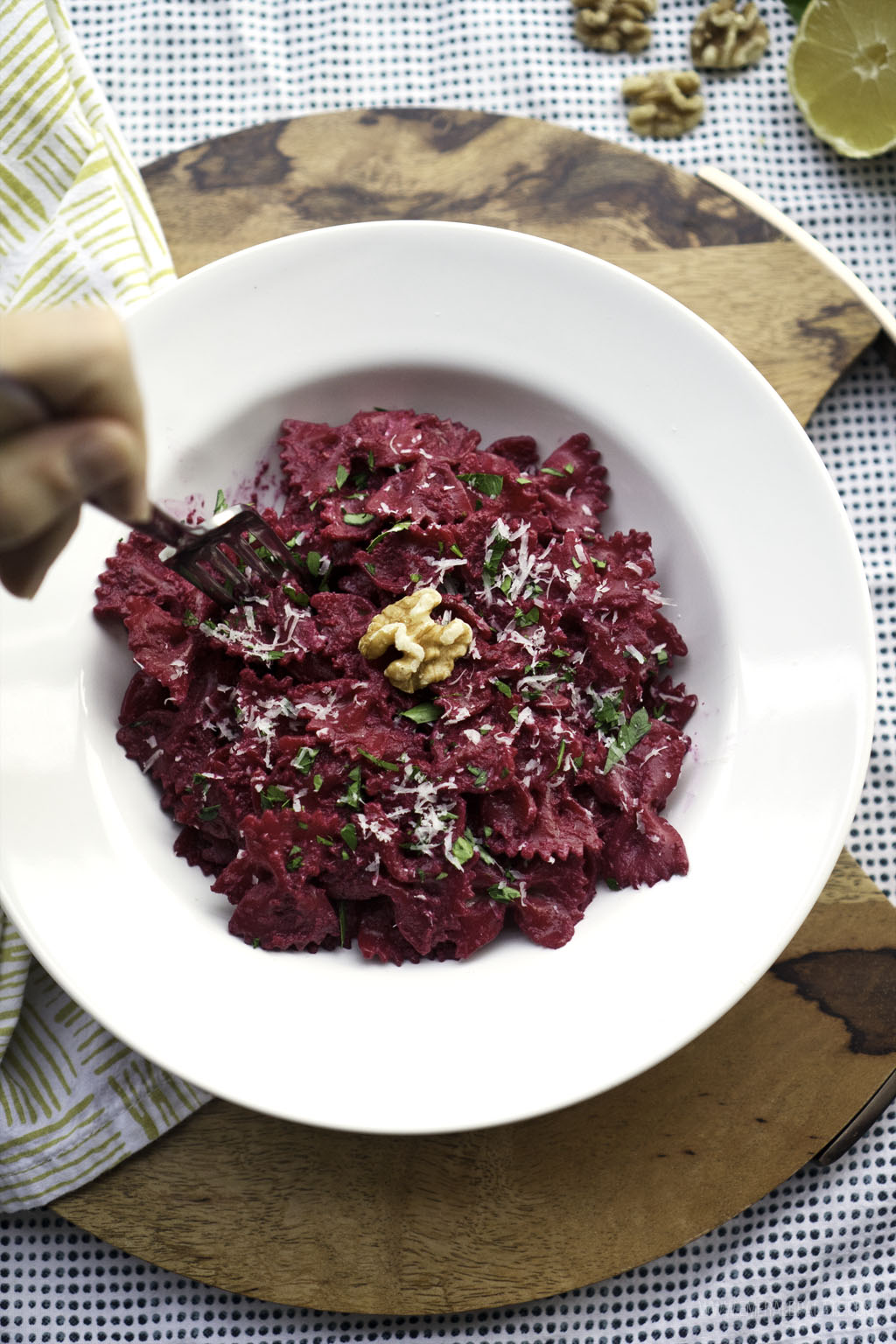 person forking bowtie pasta served with beet pesto