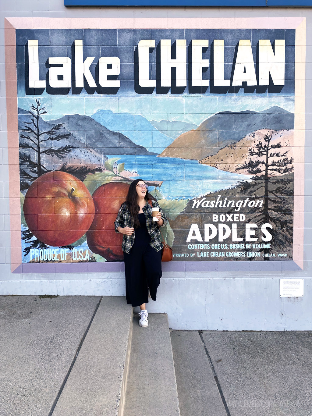 woman laughing standing in front of a mural that says Lake Chelan