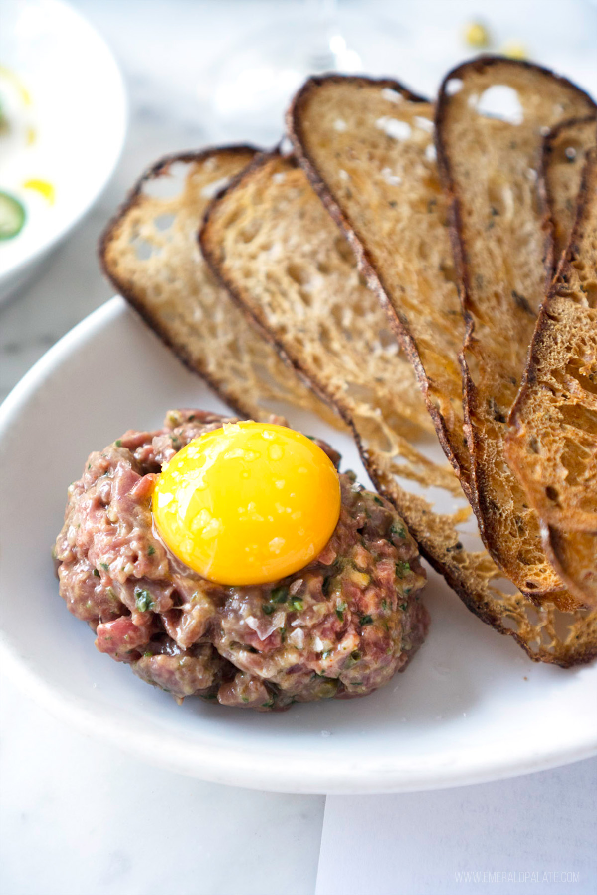Steak tartare with an egg on top and bread crostinis