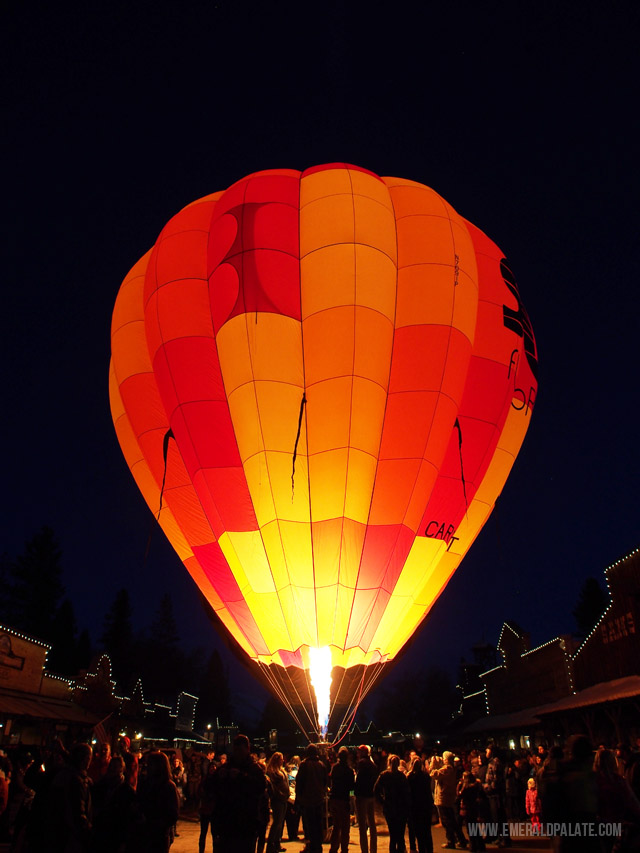 People crowded around a hot air balloon glowing in the PNW night sky at the Winthrop Hot Air Balloon Festival in central Washington.