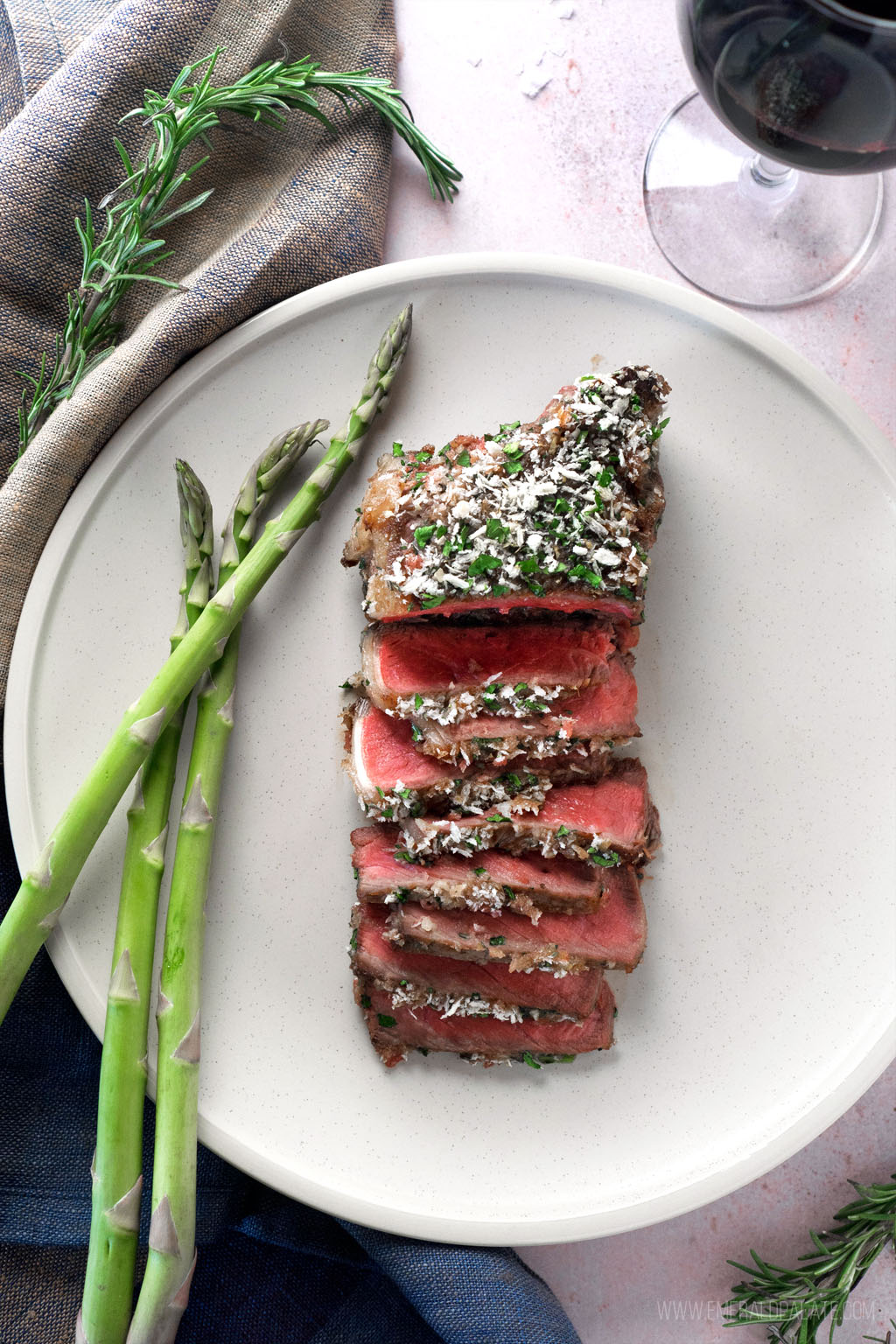 encrusted steak sliced on a plate with asparagus and wine