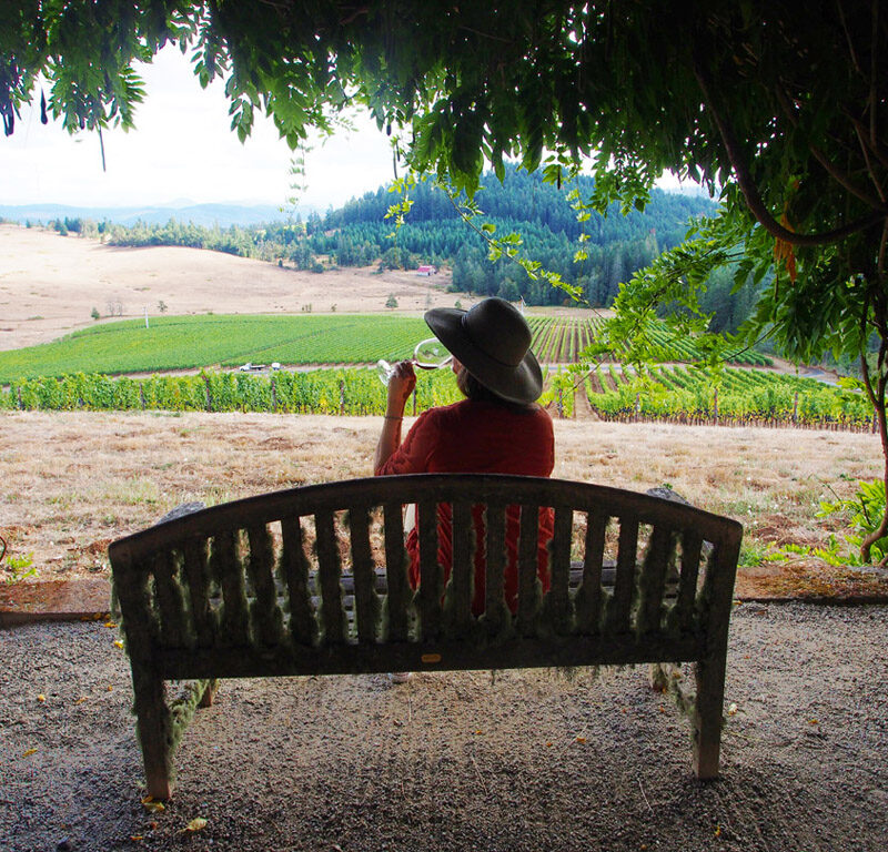woman drinking wine on a bench at one of the Willamette Valley best wineries