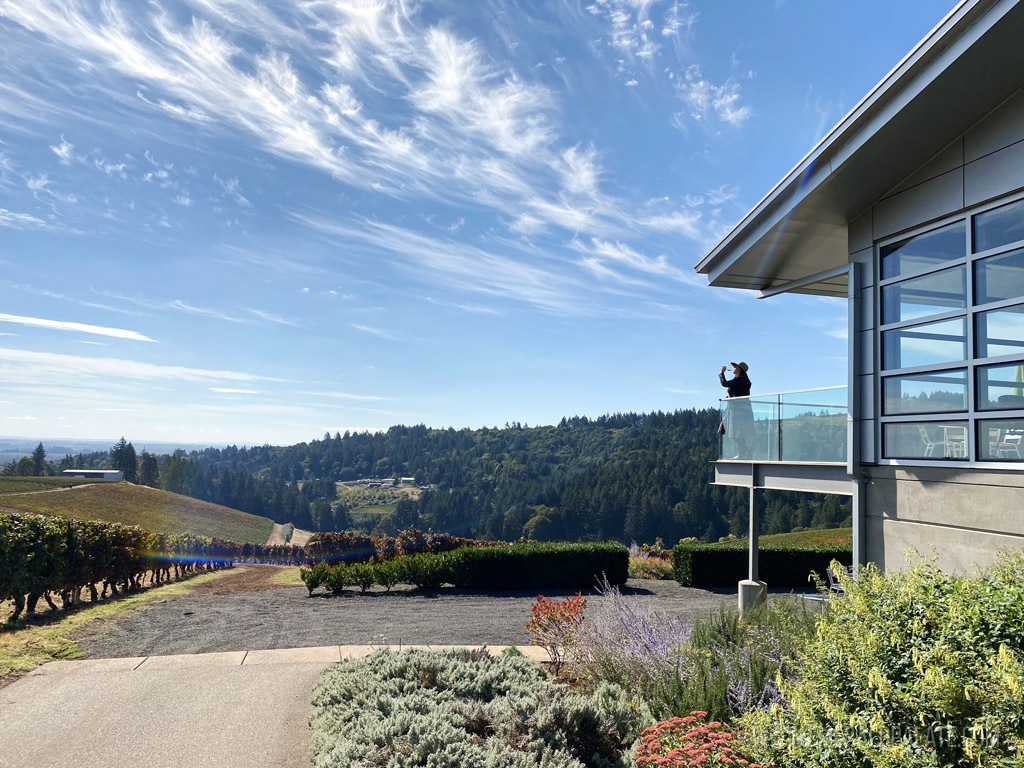 woman wine tasting on deck overlooking vineyards at one of the best wineries in Willamette Valley, Oreggon