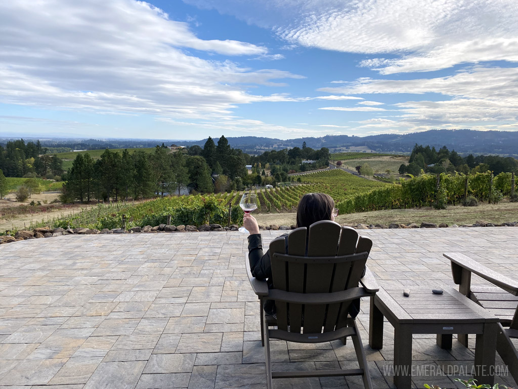woman wine tasting in an Adirondack chair overlooking Willamette Valley