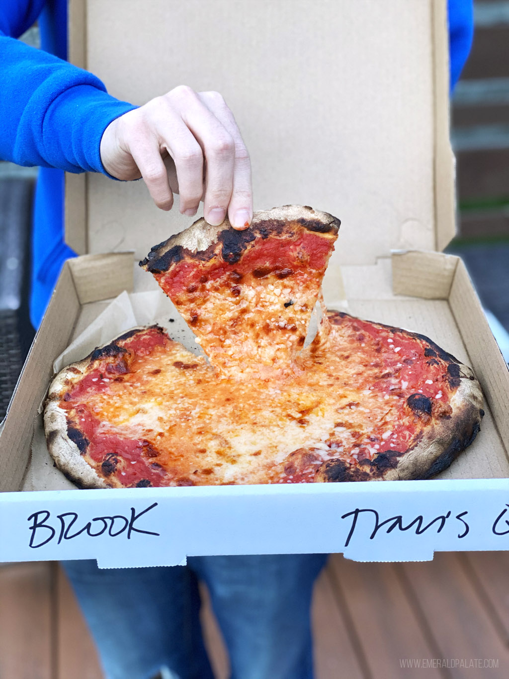 person holding up pizza from Delancey, some of the best pizza in Seattle