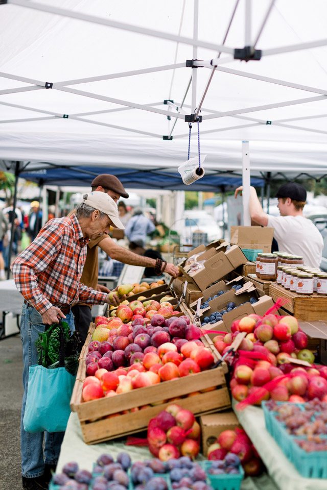 people shopping at an apple stand at a farmers market