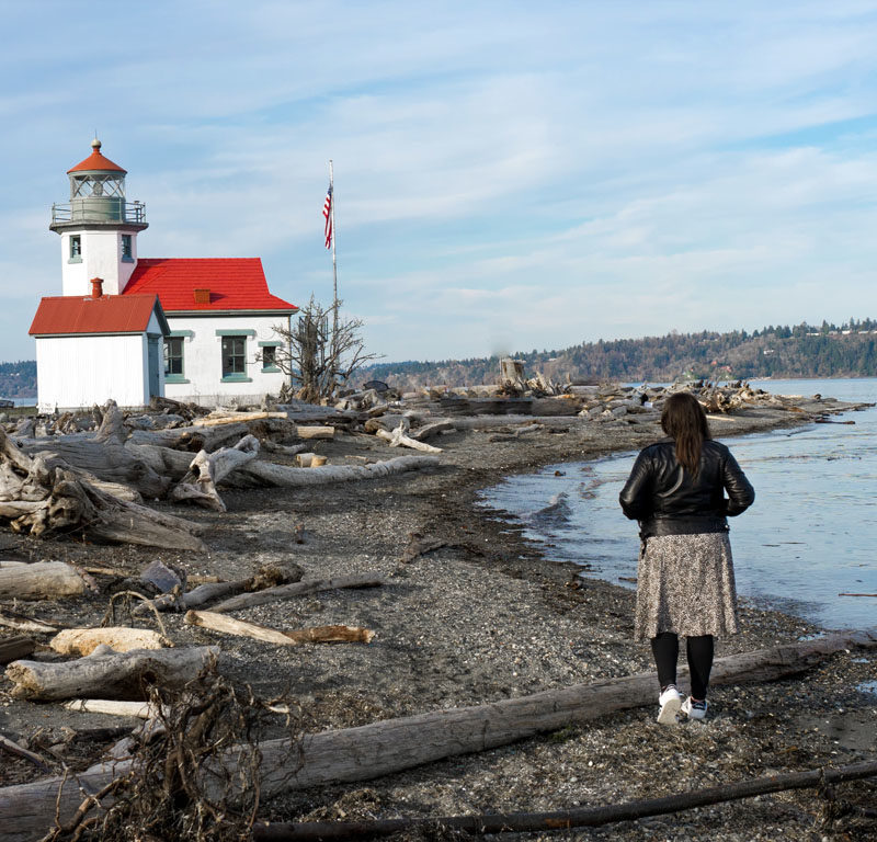 woman walking along beach at Point Robinson State Park, a thing to do on Vashon Island, WA