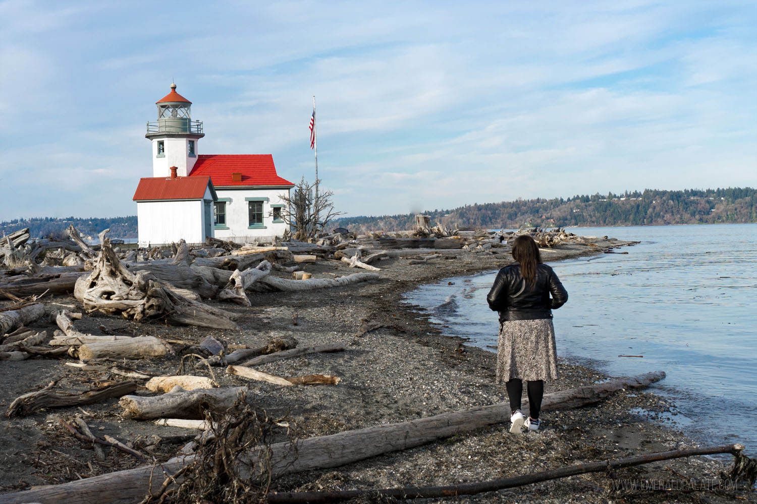 woman walking on beach in front of Pt Robinson Lighthouse on Vashon Island