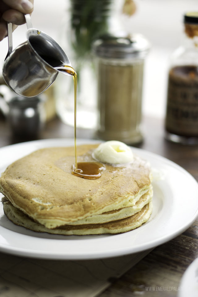 maple syrup being poured on a stack of pancakes