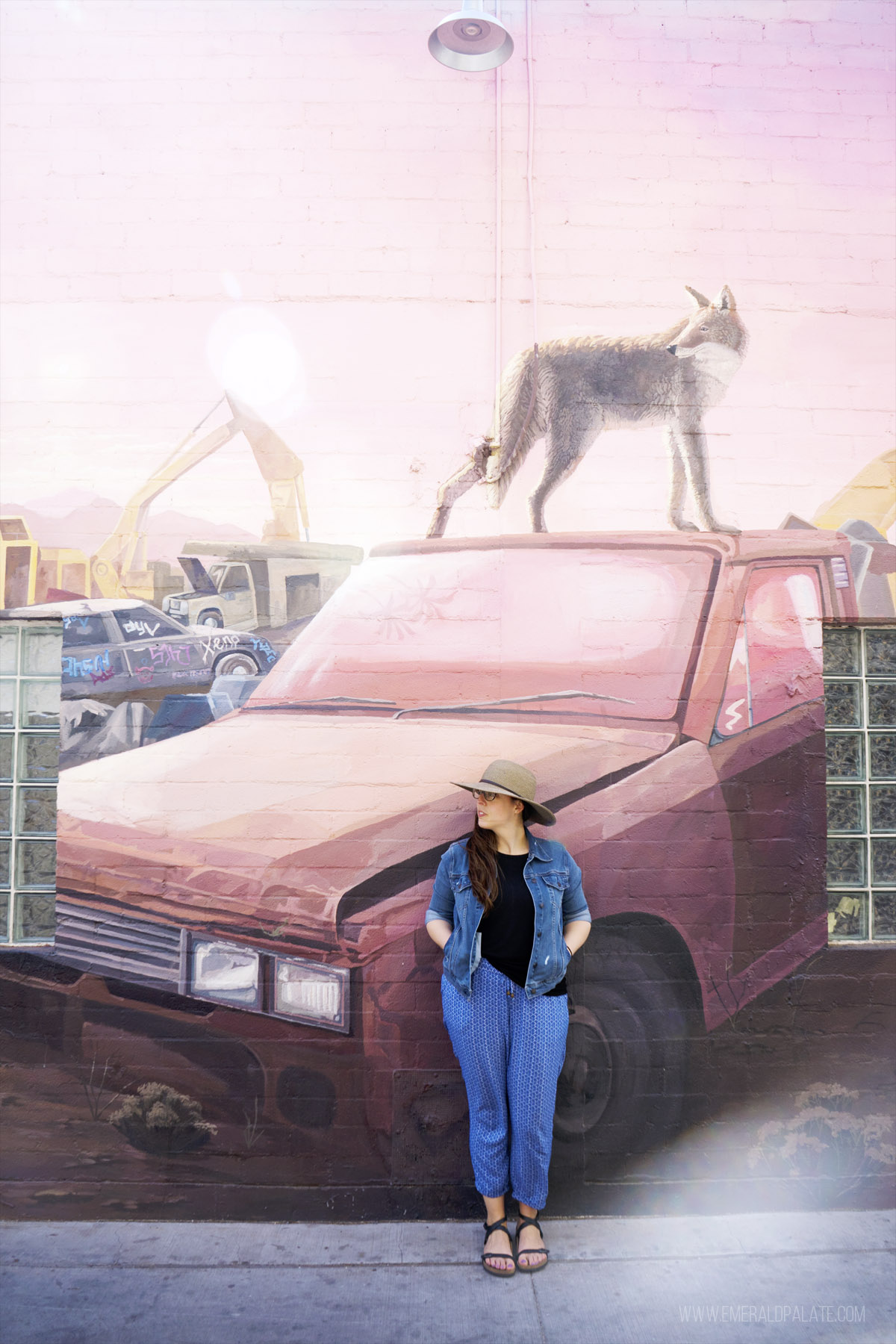 woman standing in front of a mural with a coyote on top of car, a must see in Phoenix