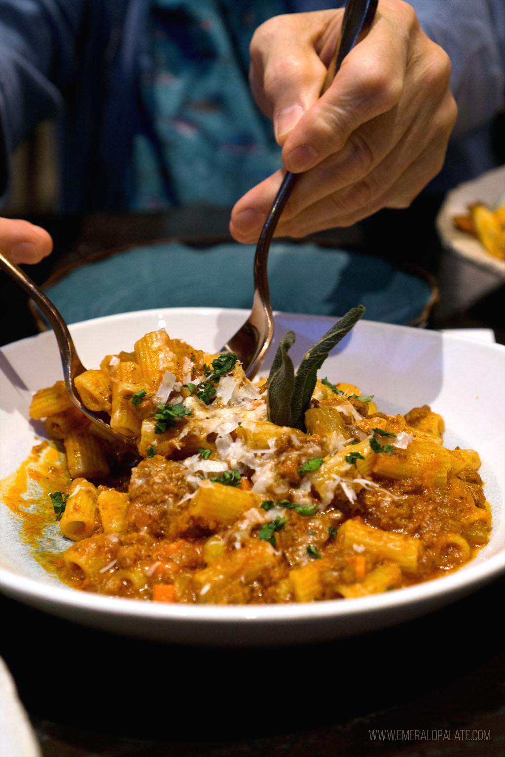 person spooning out rigatoni from a pasta dish