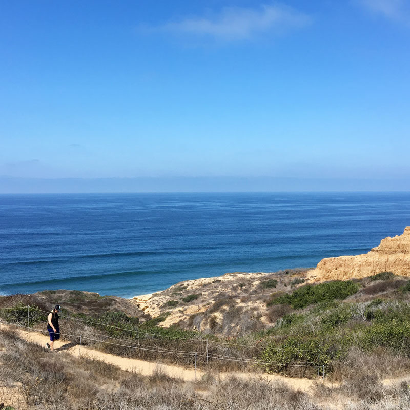 woman walking along a coastal trail during a San Diego itinerary
