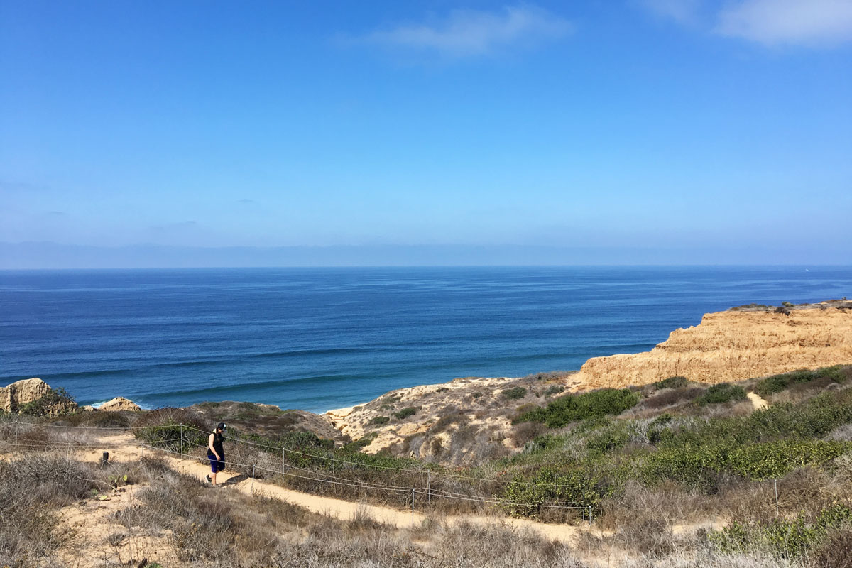woman walking along a coastal trail during a San Diego itinerary