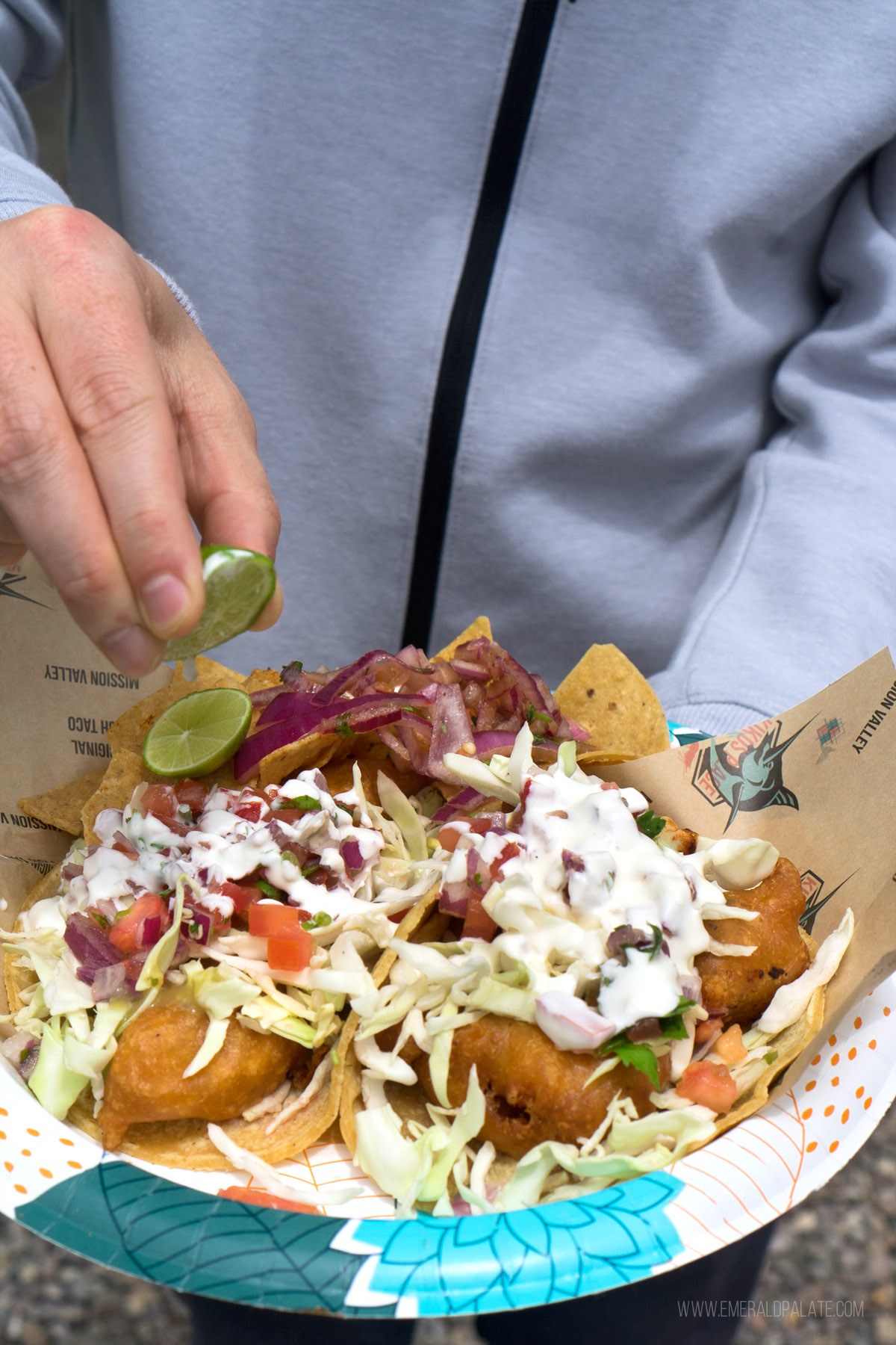 person squeezing lime over fish tacos