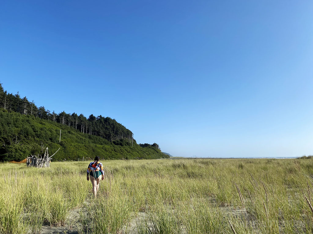 woman walking in grass on beach at Seabrook, a quaint town on the Washington coast