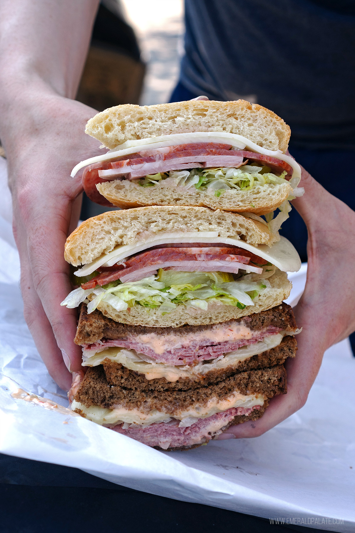 person holding stacked halves of sandwiches from a Tacoma deli