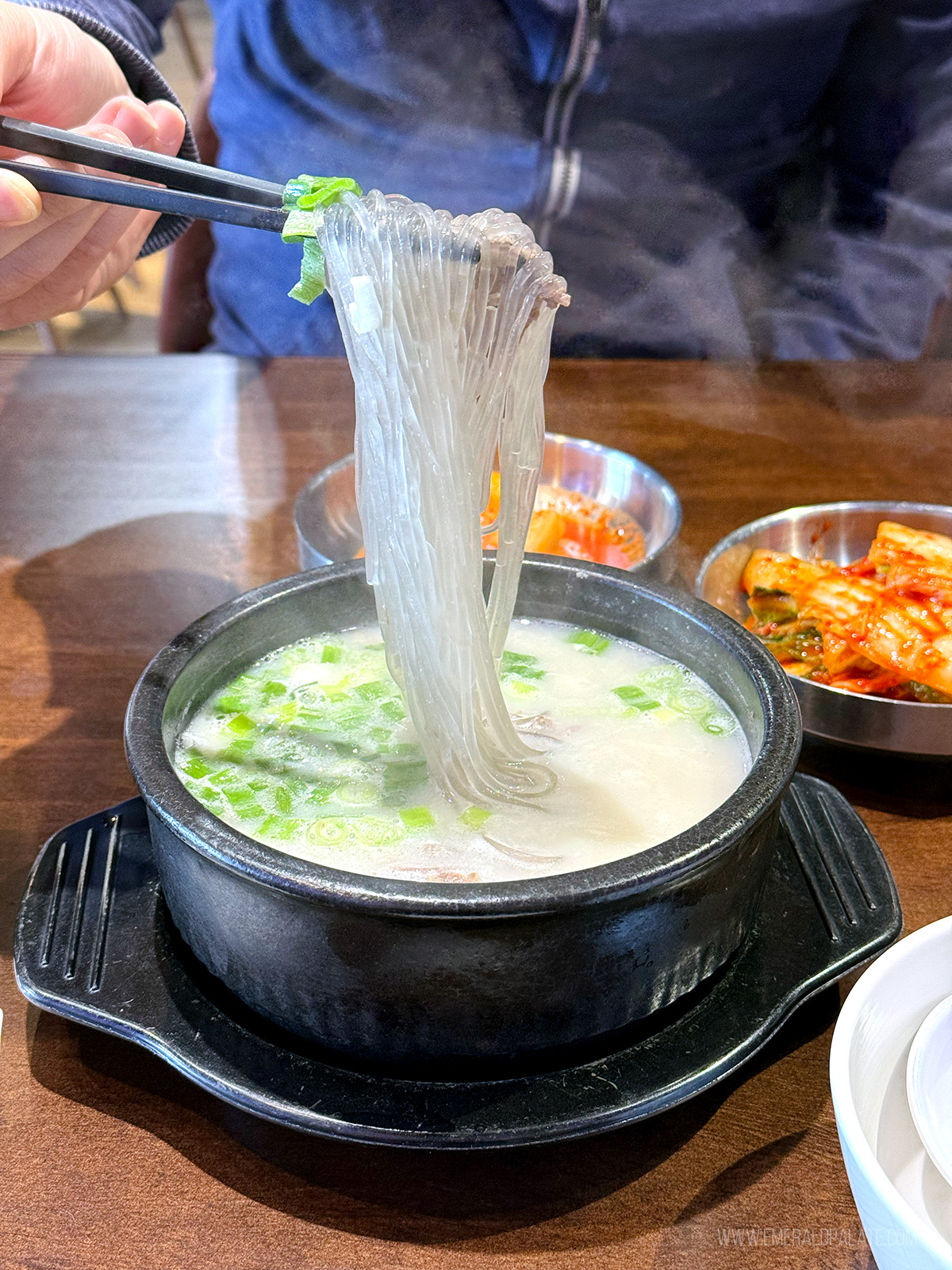 person picking up noodles with chopsticks from a Korean oxbone soup