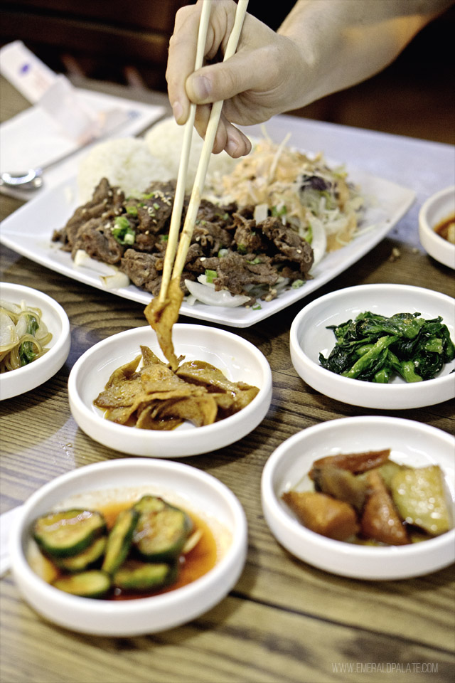 Person eating banchan with chopsticks, a Korean tradition of small plates served with dinner
