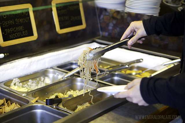 Person picking up noodles at a Korean barbecue buffet in Lakewood, WA
