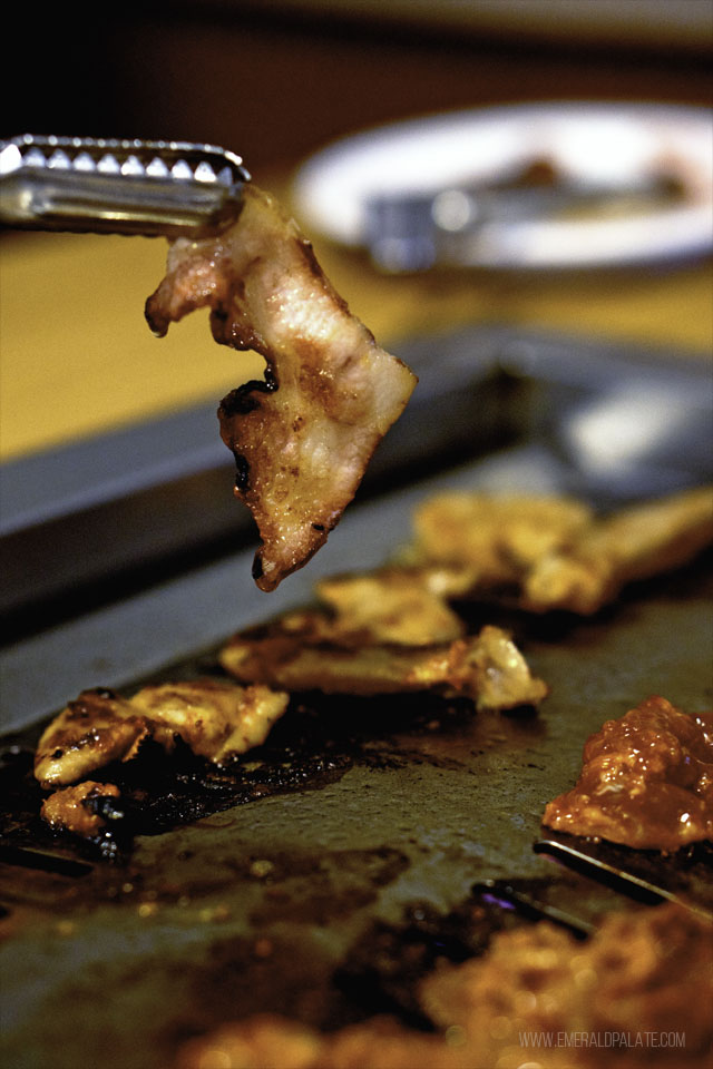 Person grilling pork jowl on a Korean barbecue in Tacoma, WA