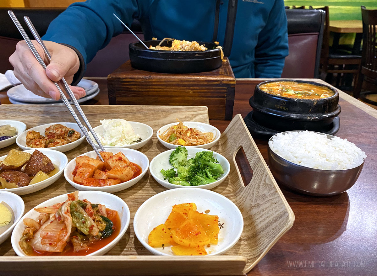 person picking up banchan at a Korean restaurant in Seattle