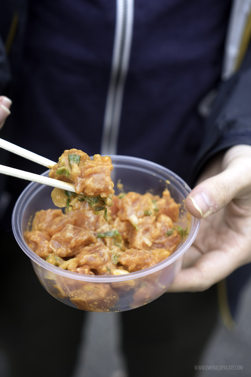 person picking up poke out of a to go container at one of the best restaurants in Edmonds, Washington