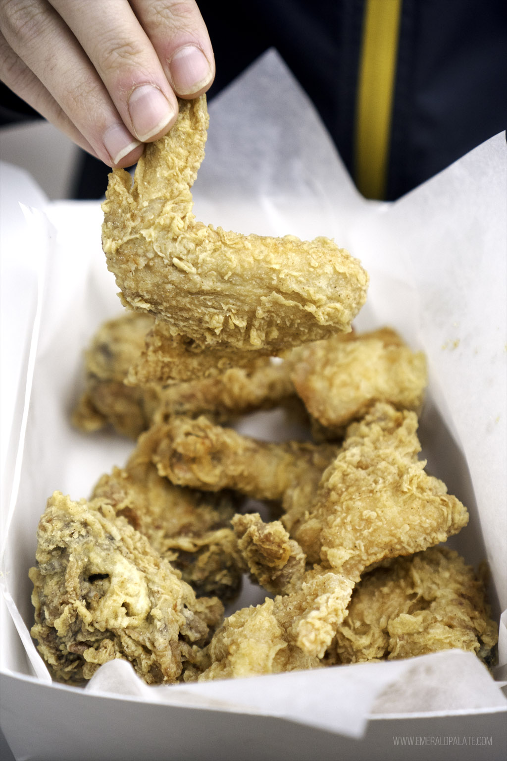 person picking up a friend chicken wing at one of the best Edmonds, Washington restaurants