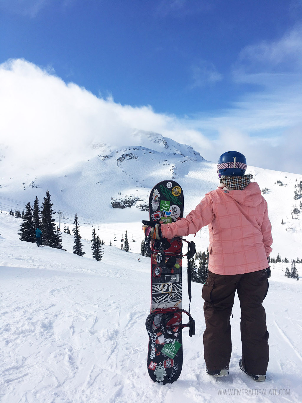 woman snowboarder standing in front of mountain at ski area