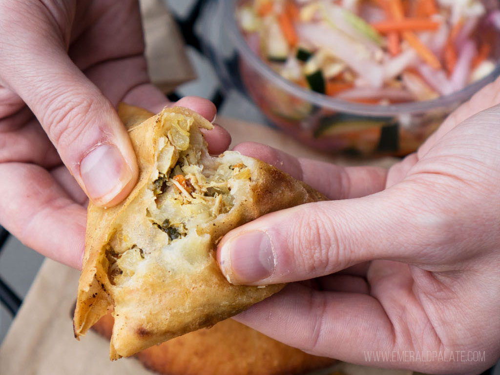 close up of person breaking apart the best cheap eats from one of the best casual restaurants in Seattle