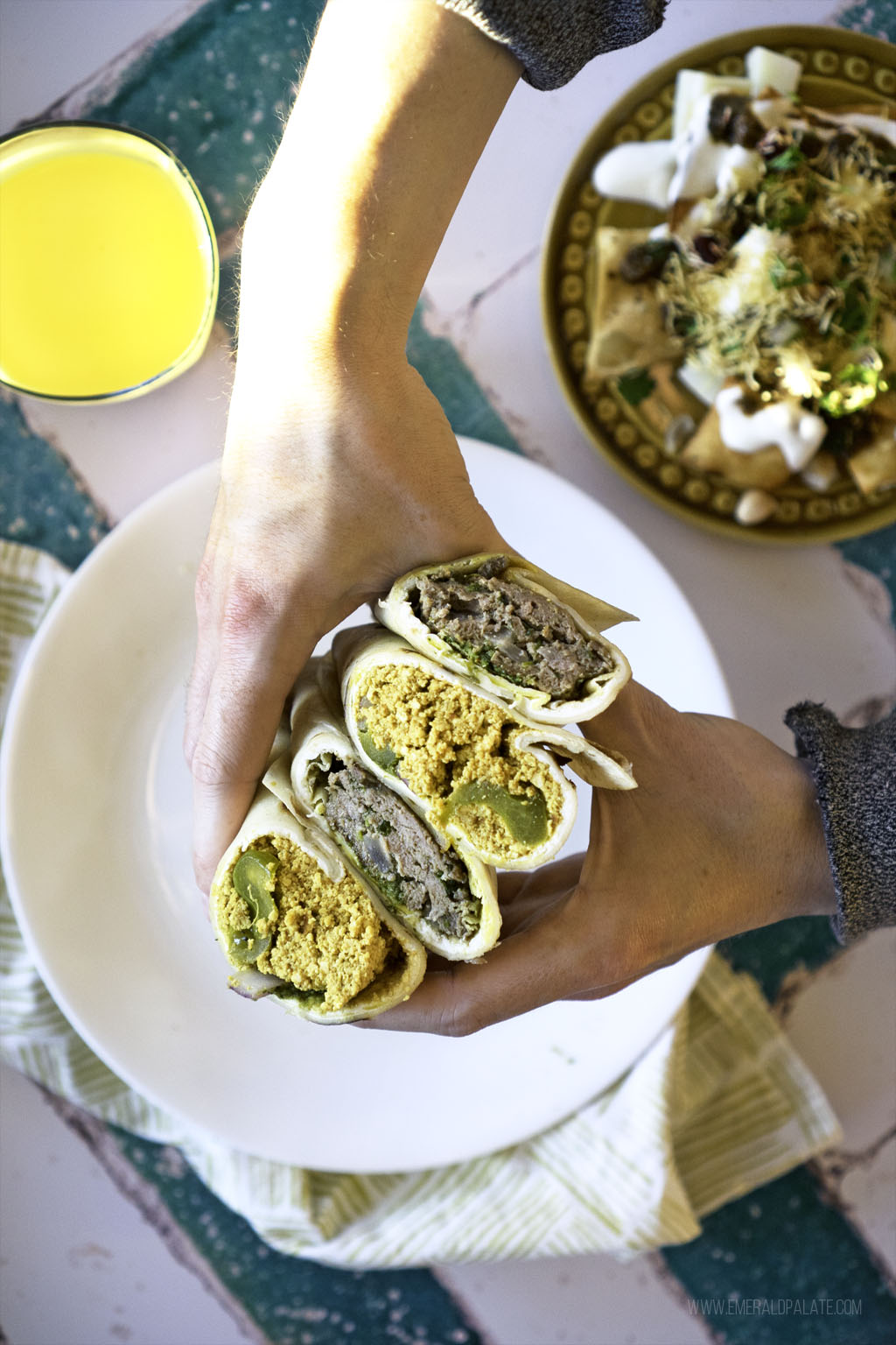 person holding stack of kathi rolls, Indian street food that makes excellent cheap eats in Seattle