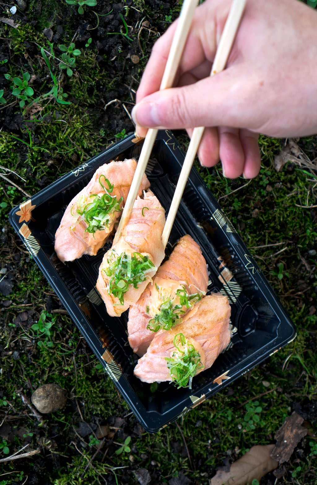 person picking up cheap sushi nigiri with chopsticks