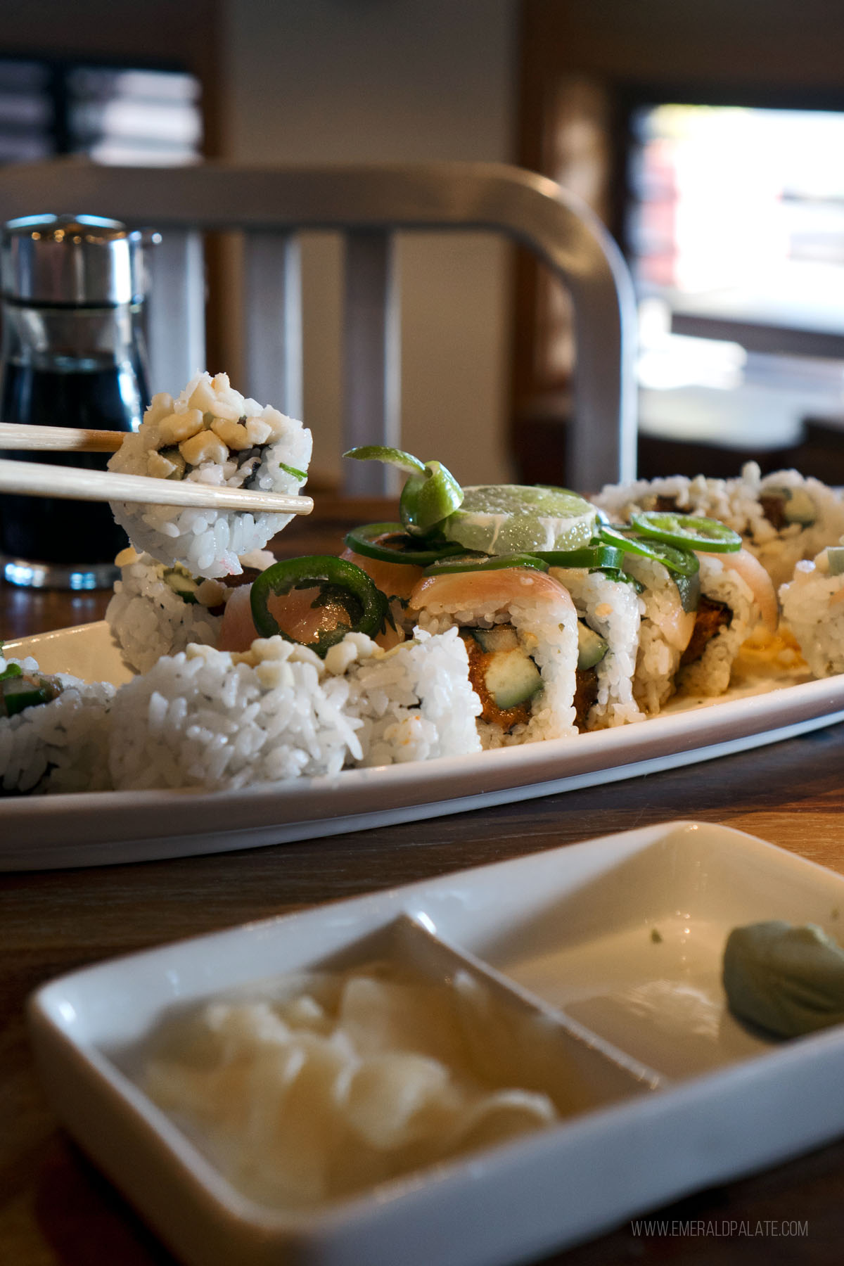 person picking up sushi roll with chopsticks