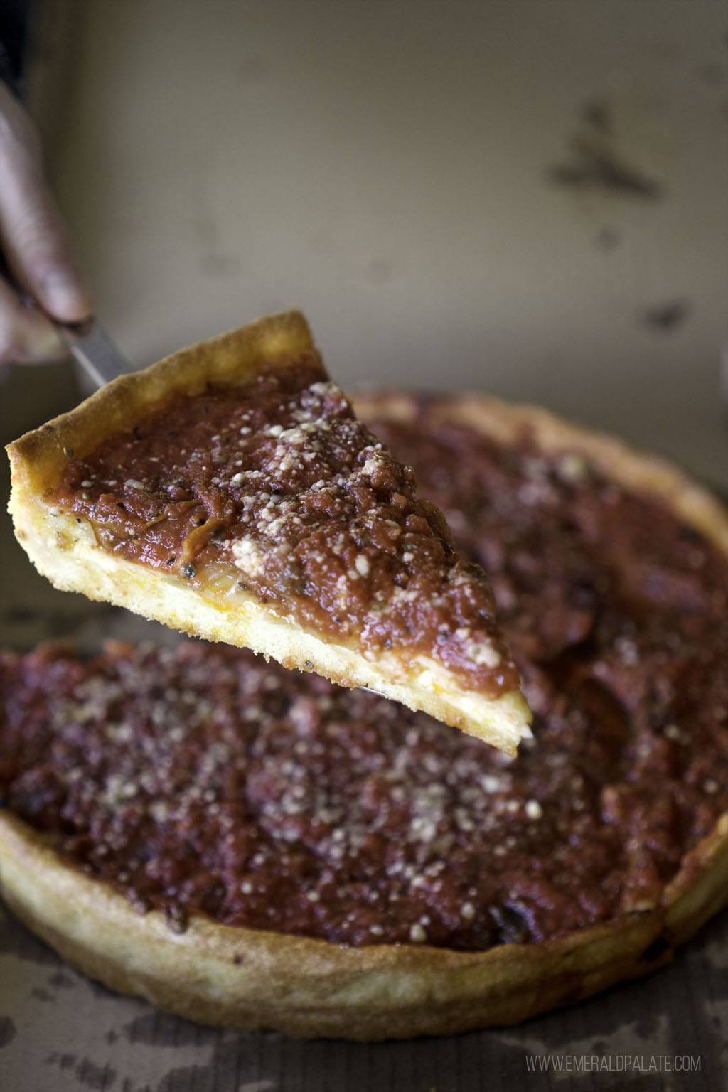 person taking slice of Chicago style pizza from Seattle