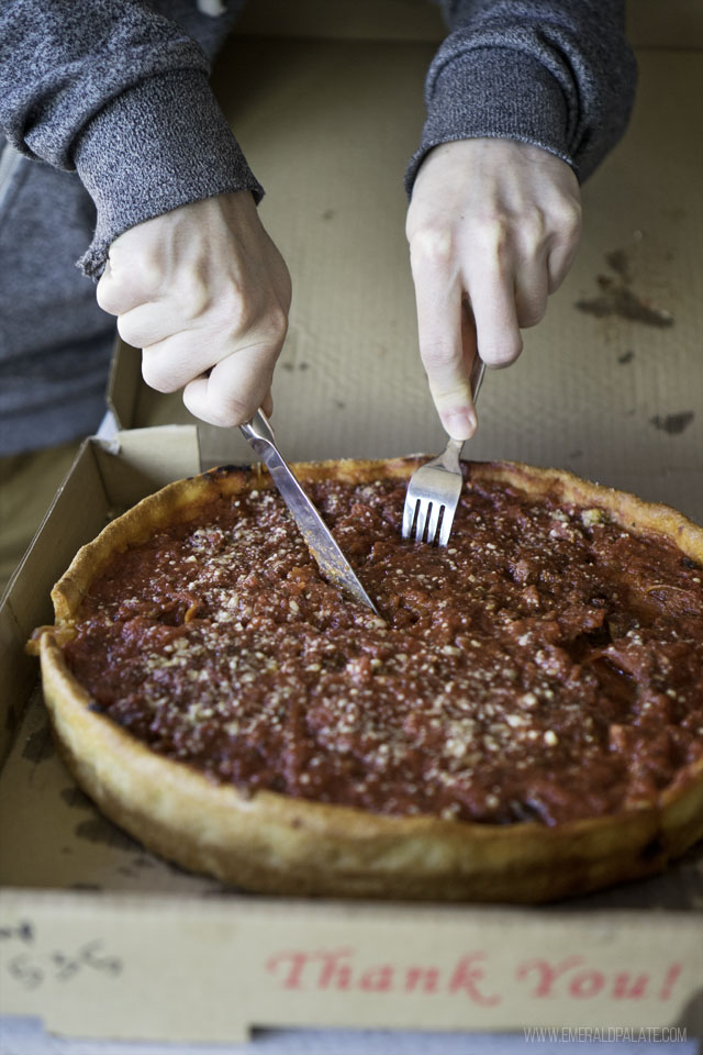person cutting into a Chicago pizza with red sauce