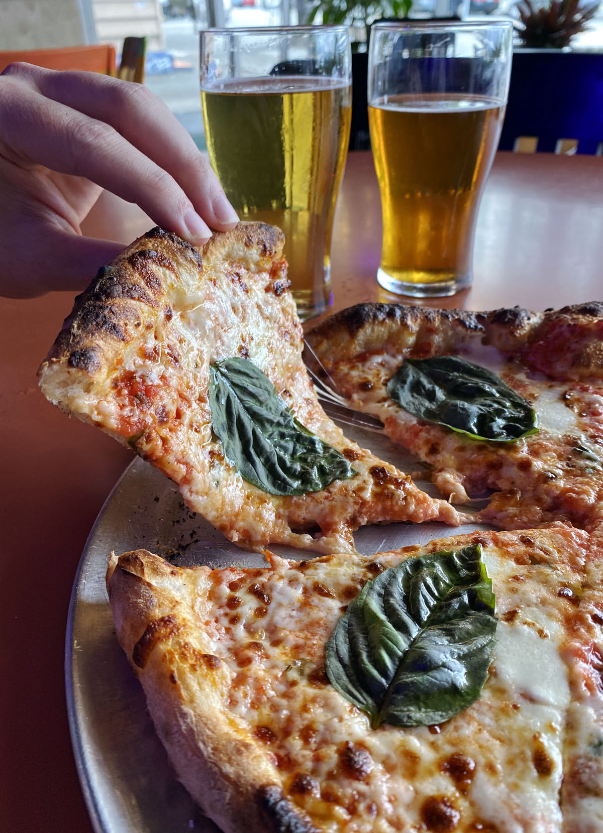 person picking up a slice of some of the best pizza in Seattle