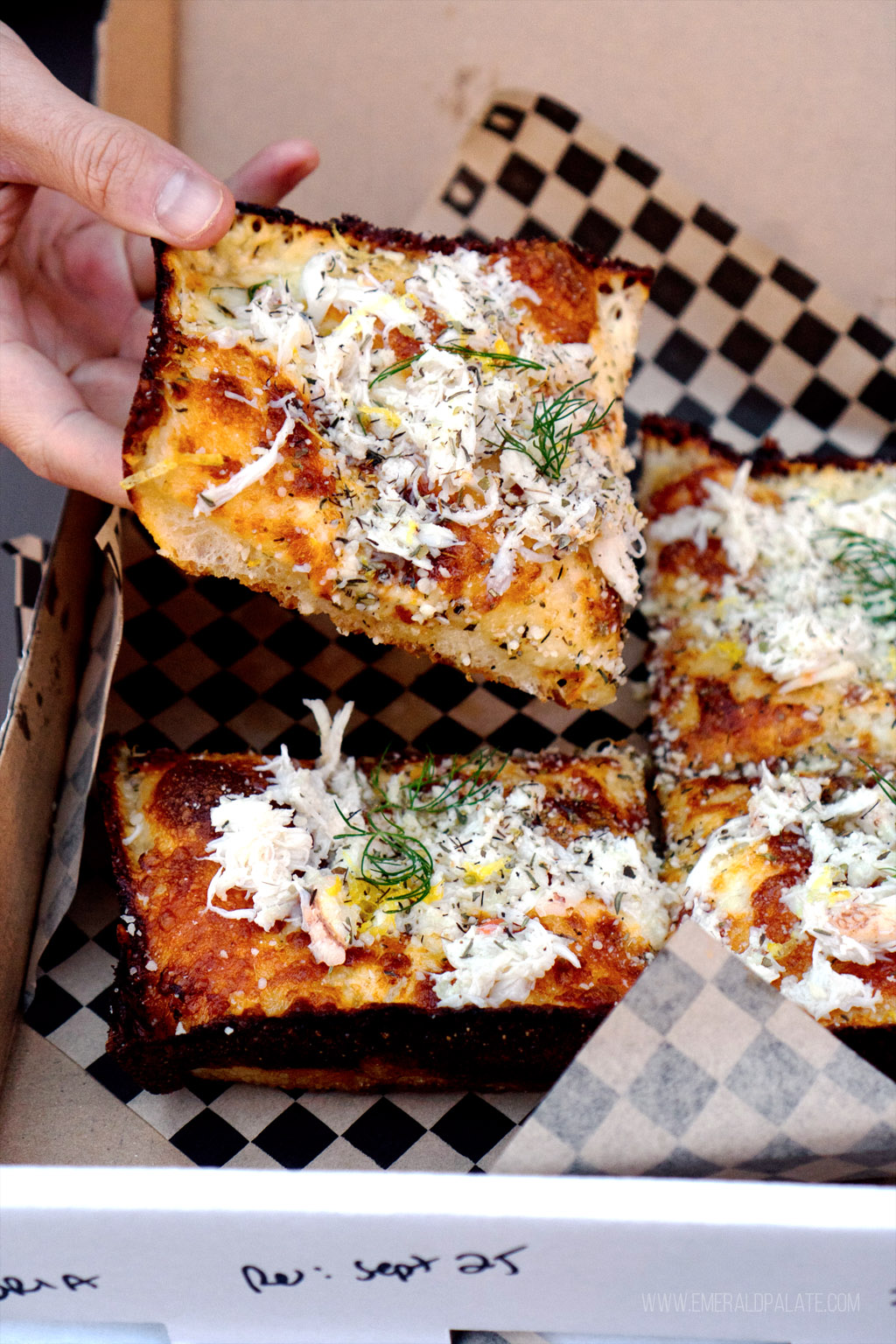 person grabbing slice of Detroit style pizza in Seattle