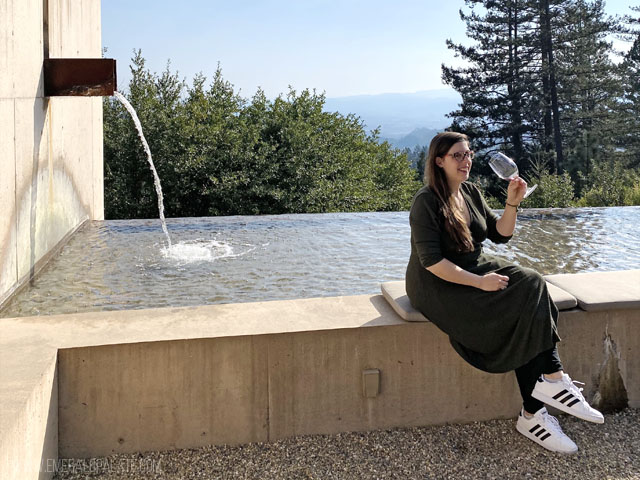 woman sipping wine on the edge of a water fountain