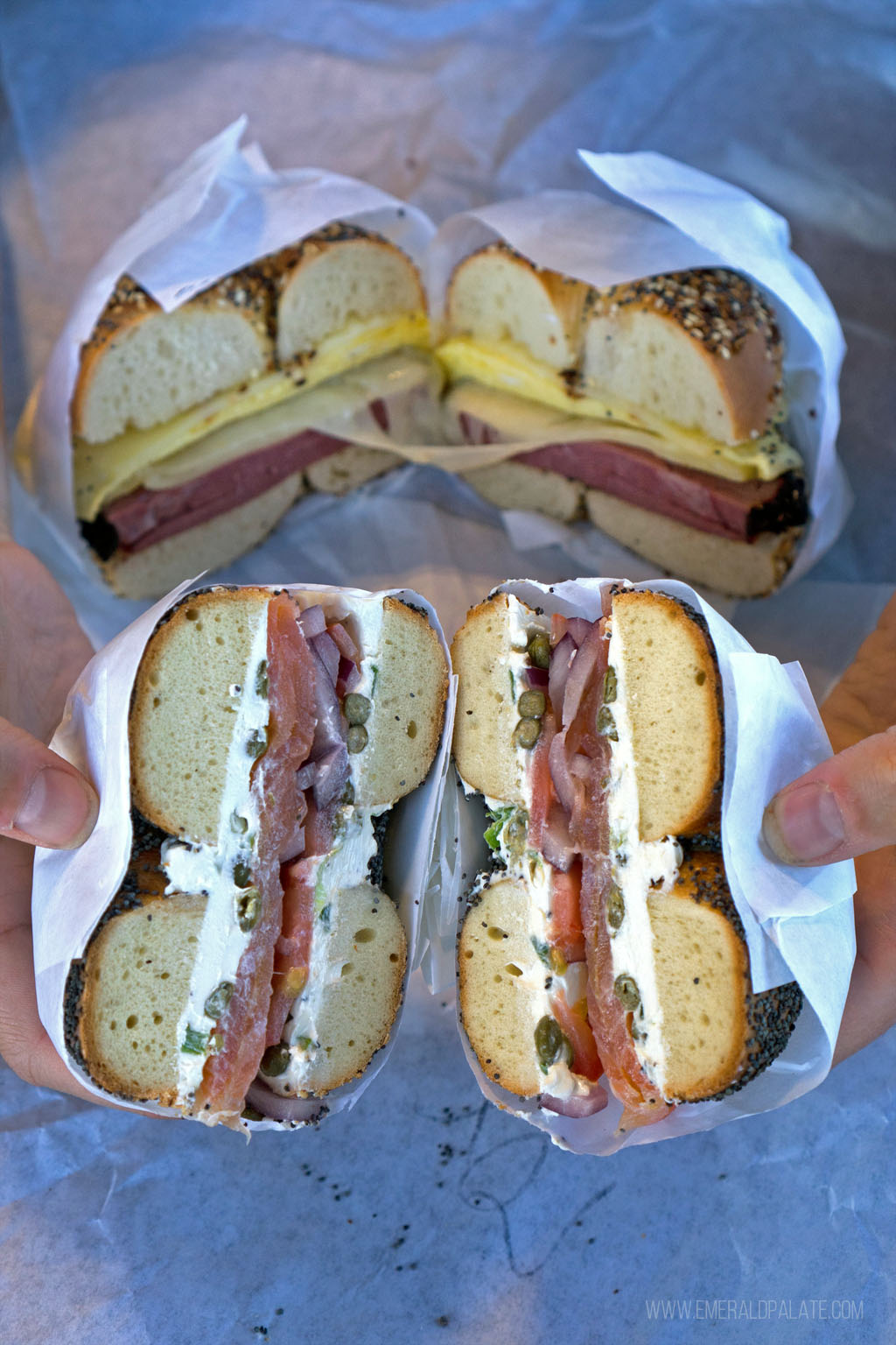 person pulling apart two halves of a bagel stuffed with lox and cream cheese