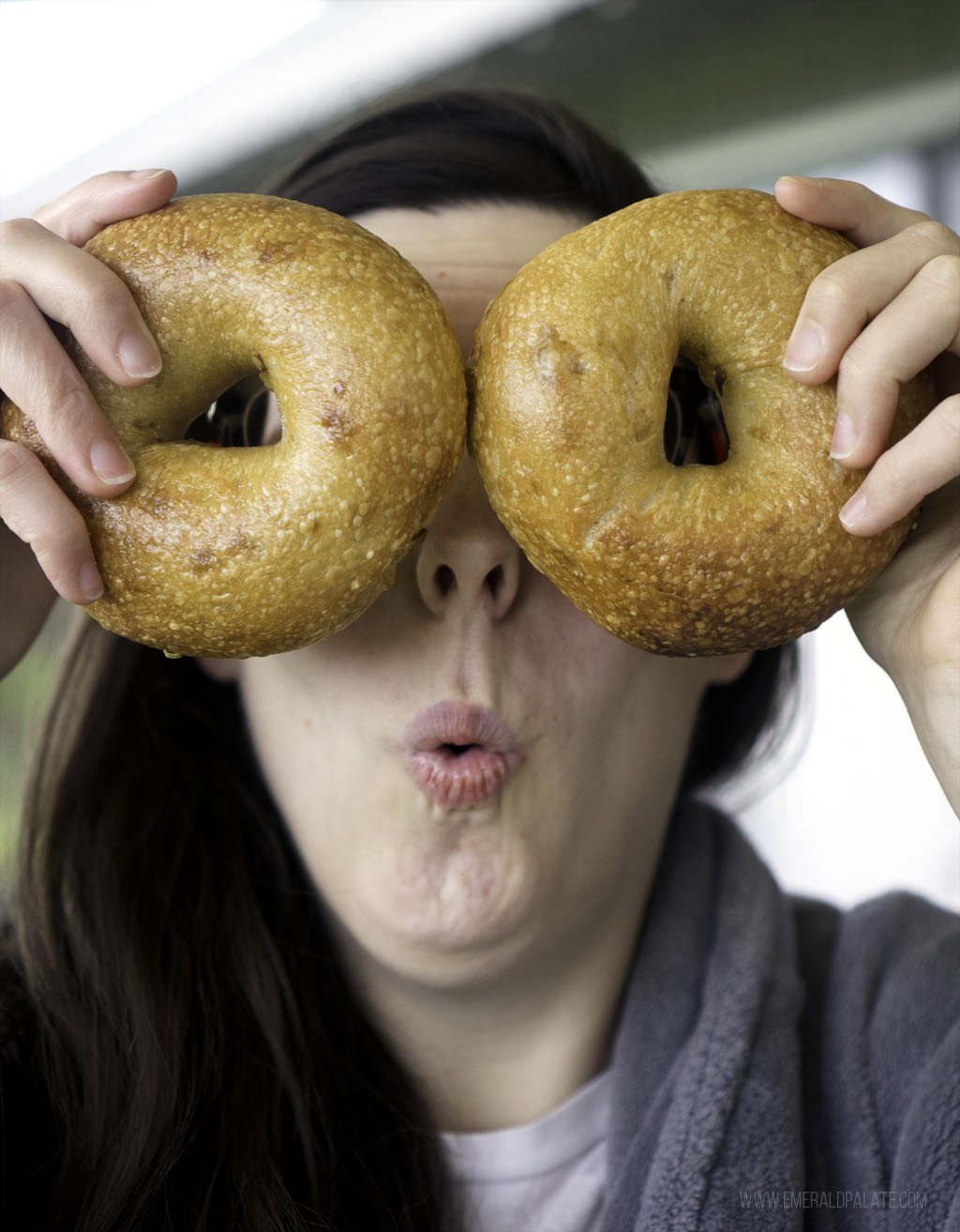 woman being silly holding two bagels over her eyes