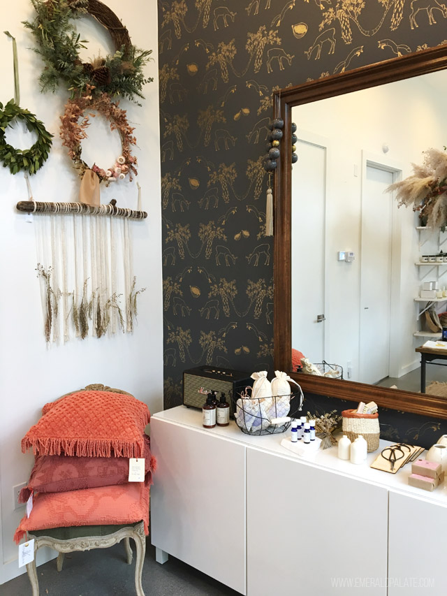 Inside a local Seattle shop with fancy wallpaper, wreaths, jewelry, and a chair