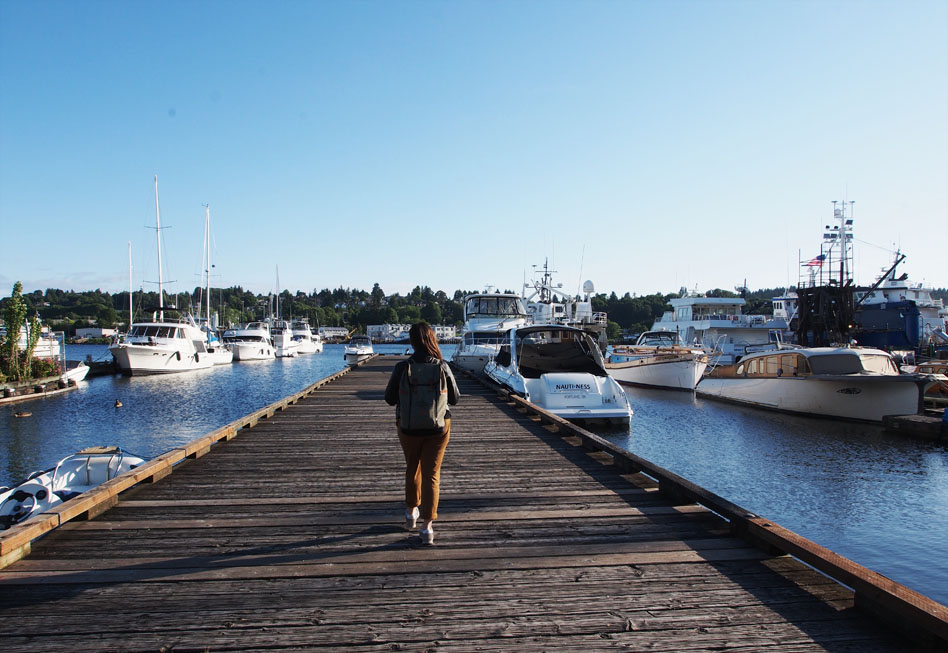 woman walking on docks by boats in Ballard, a beautiful walking food tour of Seattel