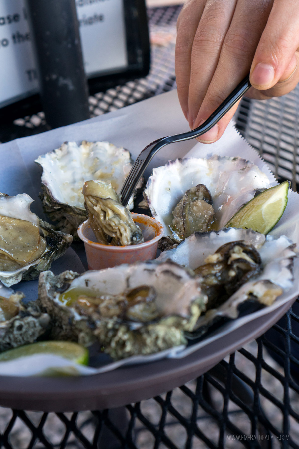 person dipping a grilled oyster into sauce