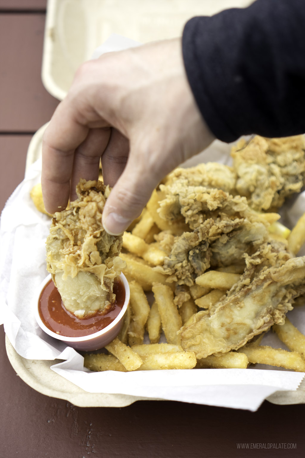 person dunking fried oyster into cocktail sauce at a Skagit County restaurant