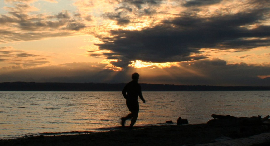 person running at sunset on beach at one of the best Seattle viewpoints